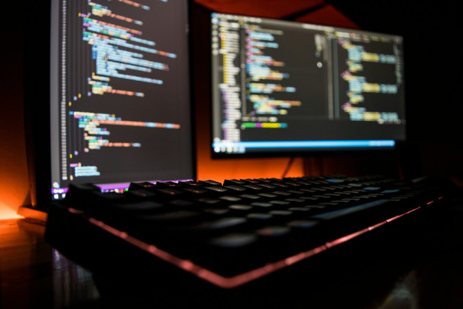 Two computer screens out of focus displaying code